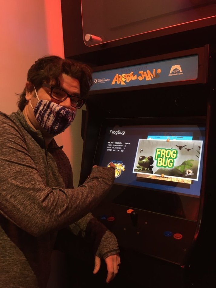Nathan Haskins pointing at the FrogBug arcade cabinet at the Saint Louis Science Center